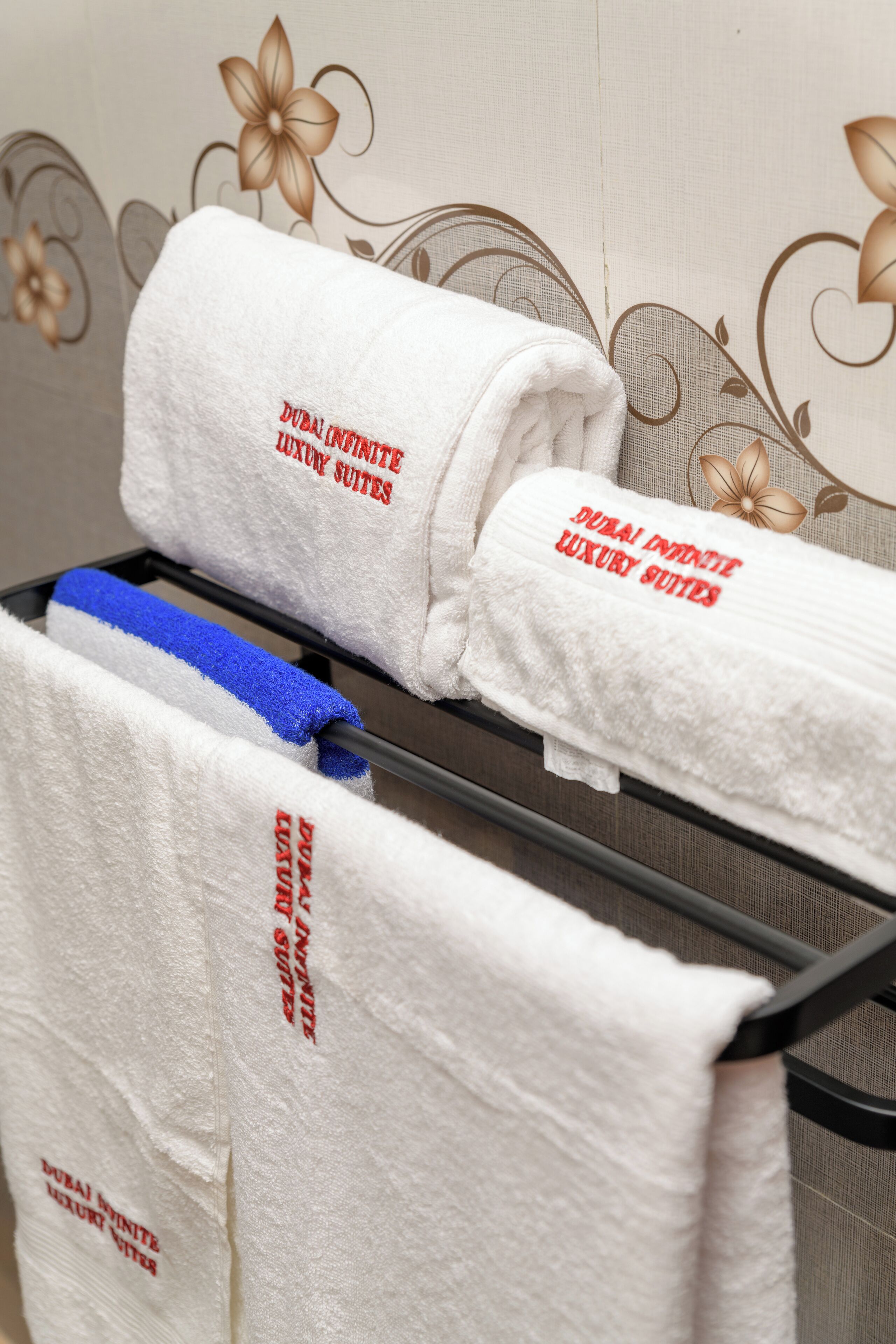 A rack with towels labeled "Dubai Innthe Luxury Suites."