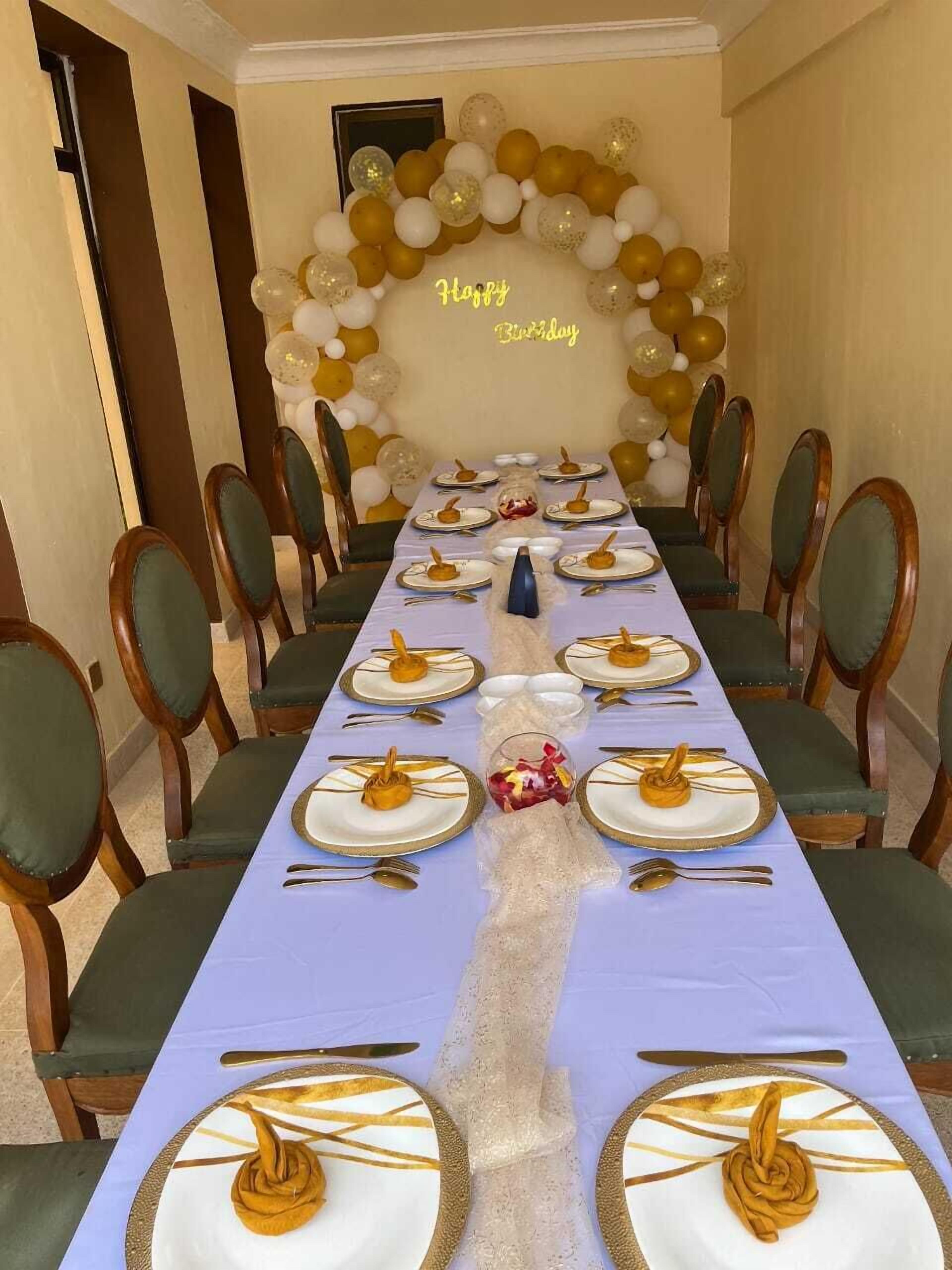 Ein langer Esstisch, festlich für einen Geburtstag gedeckt, mit einem Luftballonbogen im Hintergrund.