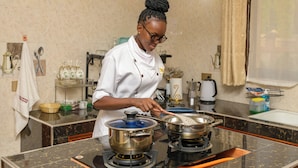 Un chef preparando comida en una cocina con encimeras de mármol, electrodomésticos de acero inoxidable y una variedad de utensilios y equipos de cocina.
