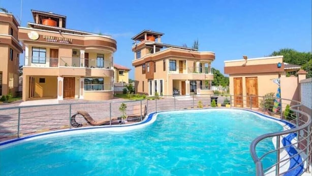 Un hotel con piscina, varios balcones y un cielo despejado.