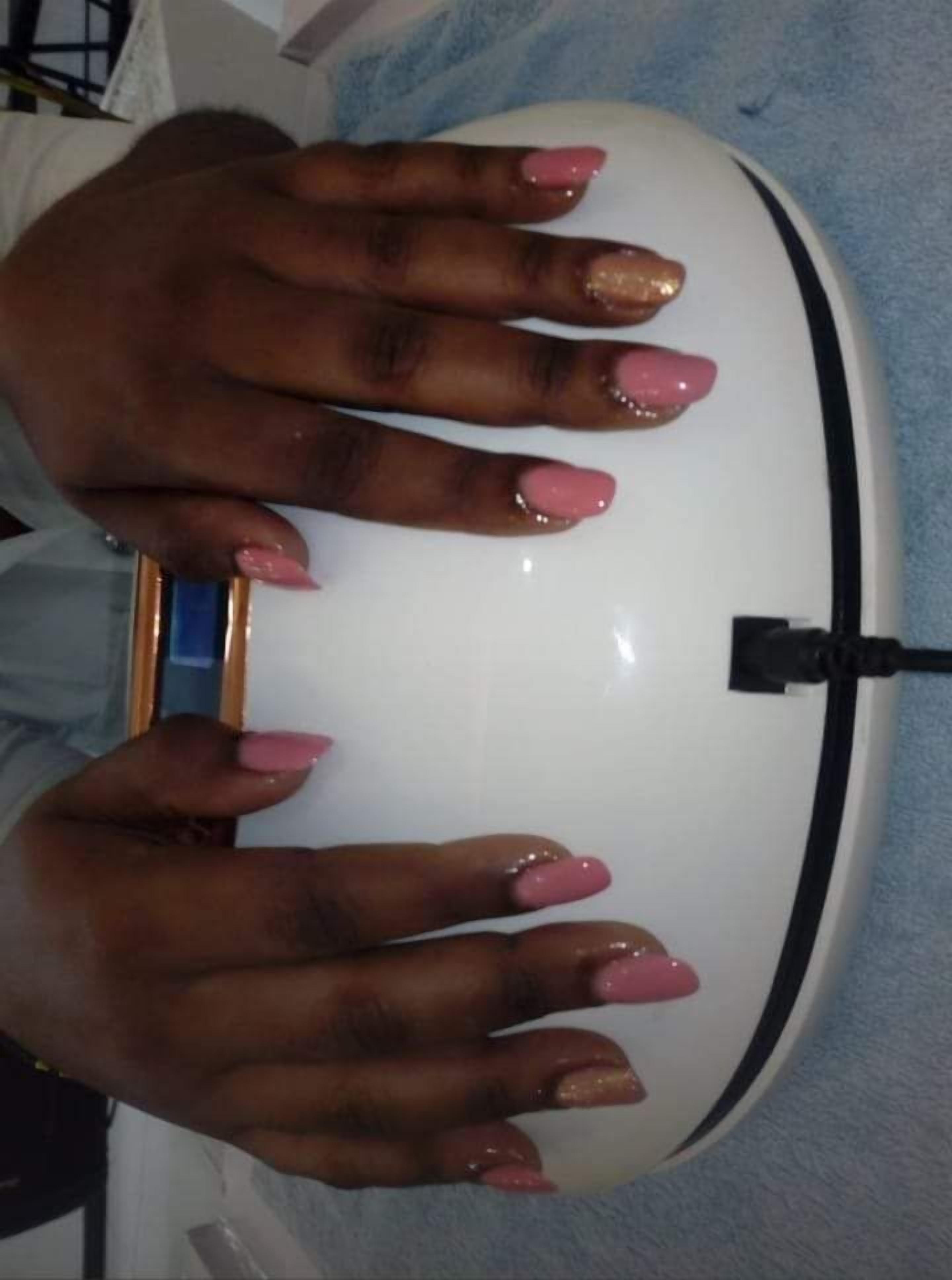 A hand with pink nail polish resting on a white and black object.