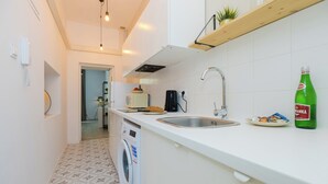 A modern kitchen with a washing machine, a coffee maker, and a bottle of soda on the counter. - ShortStayPoland Krakowskie Przedmieście (Lublin)
