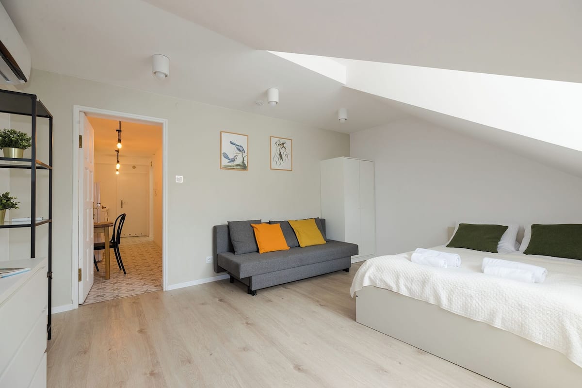A modern bedroom with a bed, a sofa, and a dining area.