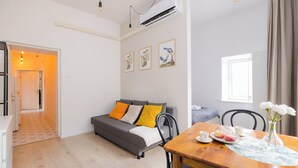 A modern living room with a grey sofa, a wooden dining table with a vase of flowers, and a kitchen visible in the background. - ShortStayPoland Krakowskie Przedmieście (Lublin)