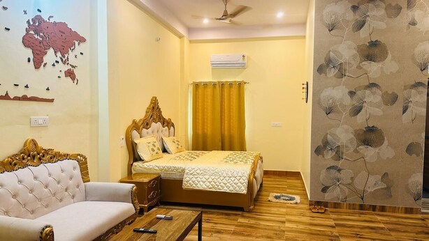 A room with a bed, a sofa, a coffee table, and a map on the wall. - Bhanu Bhawan (Jaipur)