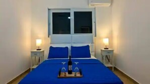 Une chambre à coucher comprenant un lit, deux tables de chevet, un ventilateur de plafond et un appareil de climatisation.