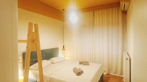 A hotel room with a bed, a wooden ladder, a window with curtains, and a wall-mounted air conditioner. - Orsiida Deluxe House Volos (Volos)