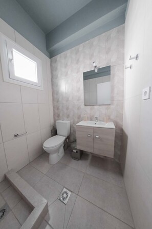 A bathroom with a toilet, sink, and mirror. - Orsiida Classic Double Room Volos (Volos)
