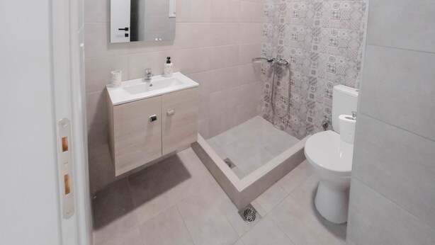 A bathroom with a white sink, mirror, and toilet, a shower area, and a green ceiling. - Orsiida Classic Double Room Volos (Volos)
