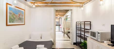 Una habitación de hotel con cama, escritorio, microondas y televisor.
