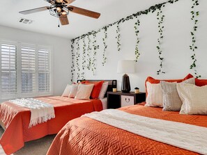 A bedroom with two beds, a ceiling fan, and a window with blinds.