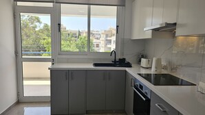 Ett modernt kök med en inbyggd ugn, en diskho och ett fönster med utsikt över ett bostadsområde.