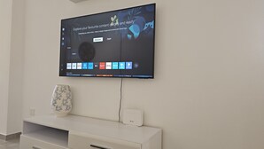 En platt-TV som är monterad på en vägg och som visar ett användargränssnitt för en smart hub, med olika appikoner.
