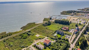 Ilmakuva rannikkokaupungista, jossa näkyy venesatama, vihreät pellot ja asuinrakennukset.