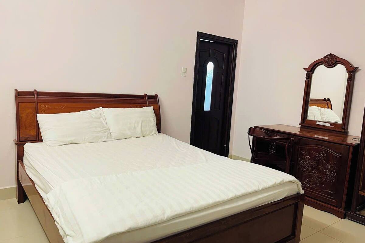 A bedroom with a wooden bed, a dresser, and a mirror.