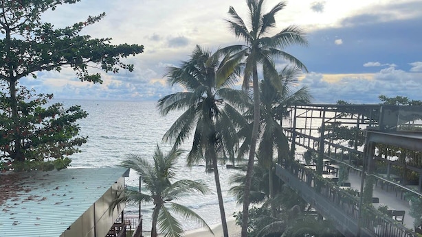 A beachside view with palm trees, a wooden deck, and a view of the ocean. - Love Phu Quoc Hotel (Phu Quoc)