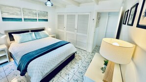 A bedroom with a bed, nightstand, lamp, and a view of the outside.