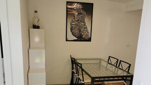 A dining area with a glass-top table, black chairs, and a white shelving unit. - 1 bedroom house 800m from the sea (Saint-Raphaël)