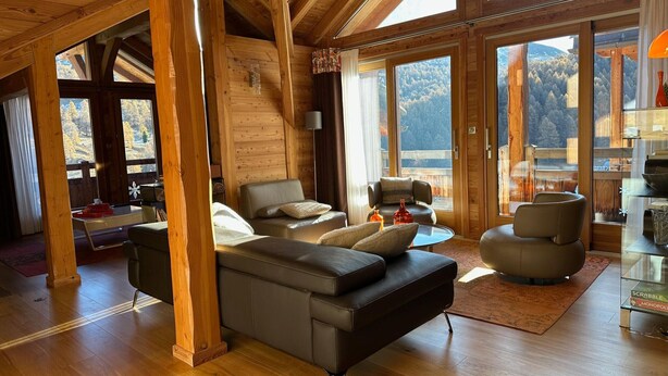 A spacious living room with a large sectional sofa, a glass coffee table, and multiple seating options. The room features wooden beams, large windows, and a view of the outdoors. - Luxury 4* Chalet with Jacuzzi and Sauna (Vars)