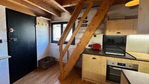 A compact kitchen with wooden beams, a black door, a red toaster, and a stainless steel oven. - Studio Vars, studio flat, 4 persons (Vars)