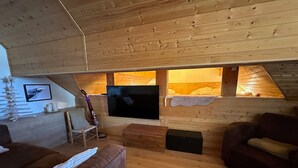 A cozy loft bedroom with a wooden ceiling, a large TV, a bunk bed, and a wooden floor. - Studio Vars, studio flat, 4 persons (Vars)
