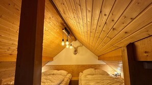 A cozy attic bedroom with two beds, wooden beams, and a sloped ceiling. - Studio Vars, studio flat, 4 persons (Vars)