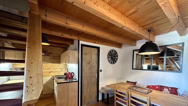A cozy wooden interior with a kitchen area, a dining table, and a sofa. - Studio Vars, studio flat, 4 persons (Vars)