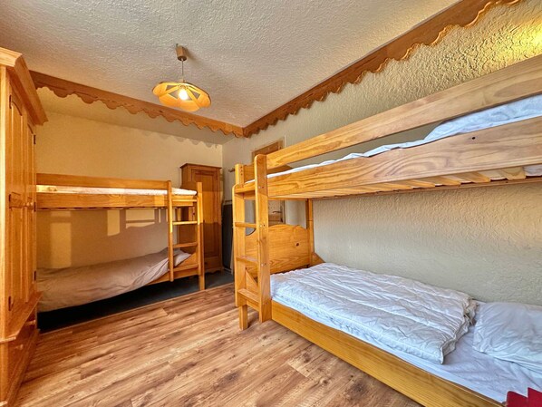 A bunk bed room with wooden bunk beds, a wooden wardrobe, and a ceiling light fixture. - T3 Apt in Vars Center, Ideal for 6, Steps from Slopes (Vars)