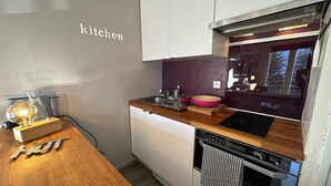 A compact kitchen with white cabinets, a wooden countertop, a built-in oven, and a window offering a view.