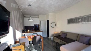 A compact living space with a dining area, kitchenette, and a sofa.