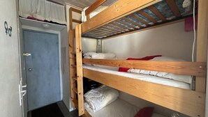 A bunk bed room with a door, a small window, and a ceiling fan.