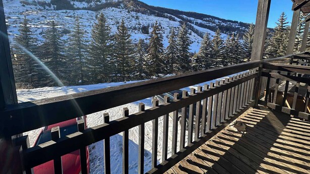 A wooden balcony with a view of a snow-covered mountain landscape.