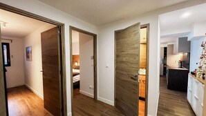 Corredor com piso de madeira e portas que dão acesso a quartos e uma cozinha.