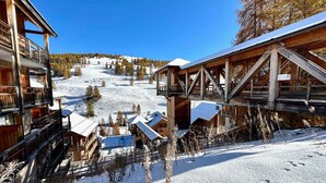 A wooden lodge with multiple balconies and a ski lift in the background. - Apartment Vars, 1 bedroom, 4 persons (Vars)