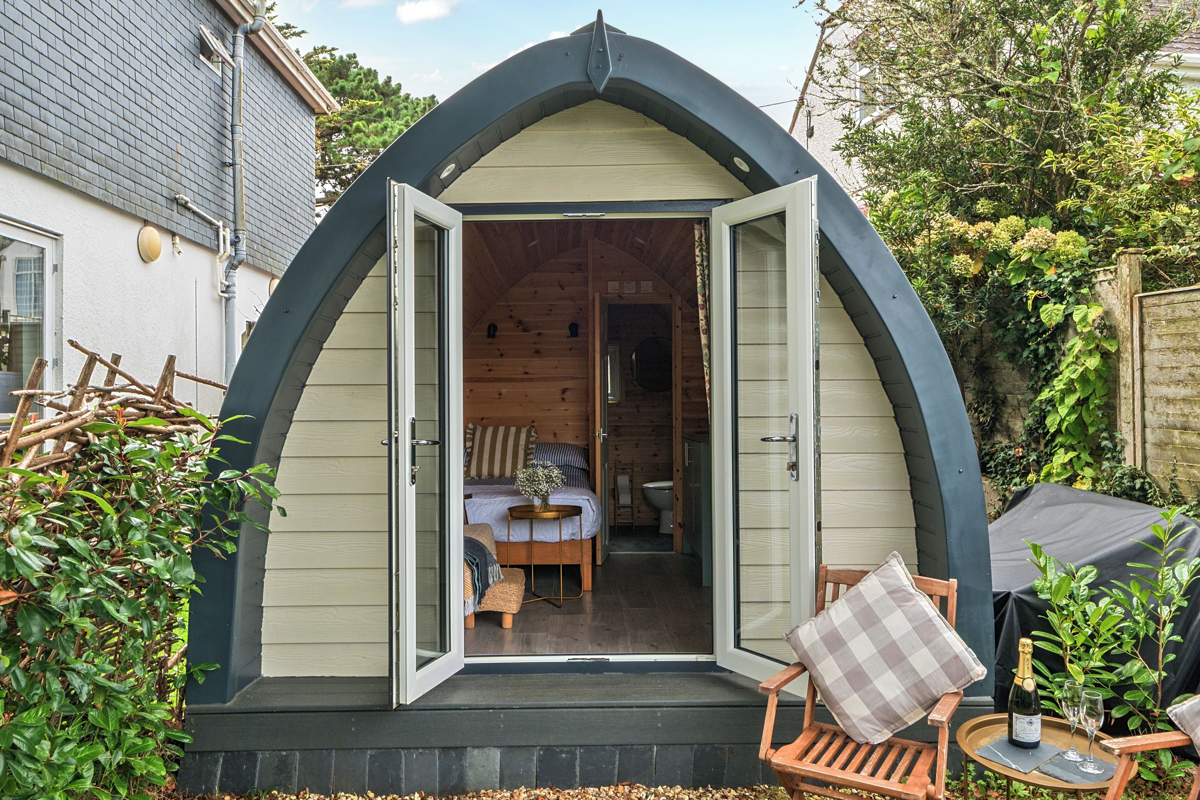 A cozy, semi-open cottage with a wooden interior, a small dining area, and a garden view.