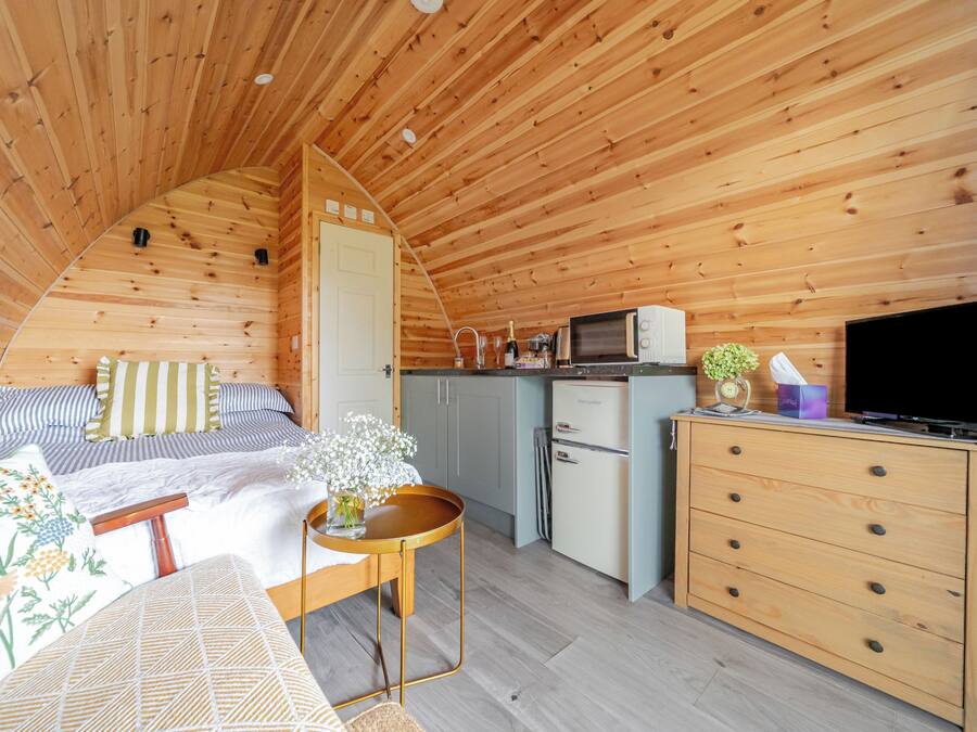 Een gezellig houten huisje met een bed, kitchenette en een televisie.