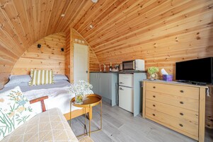 Interior acogedor de una cabaña con cama, kitchenette y televisión.