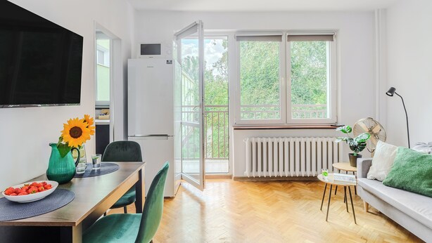 Ein moderner Wohnraum mit Essbereich, einer Couch und einem großen Fenster mit Blick auf Grünflächen.