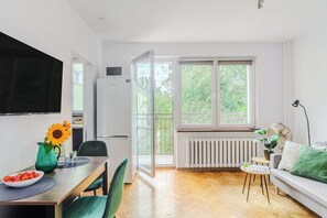 Een moderne leefruimte met een eethoek, een bank en een groot raam met uitzicht op groen.