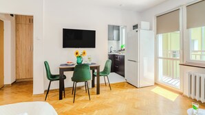 Eine moderne Küche mit Essbereich, einem an der Wand befestigten Fernseher und Blick auf den Balkon.