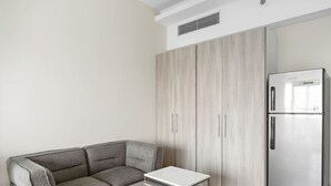 A modern kitchen with a built-in refrigerator, a grey sofa, and a small table. - Chic Studio Near Burj Khalifa, Dubai Opera & Dubai Mall w/ City Skyline Views (Dubai)