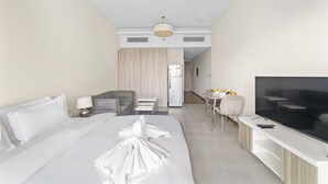 A modern hotel room with a large bed, a TV, a desk, and a kitchenette. - Chic Studio Near Burj Khalifa, Dubai Opera & Dubai Mall w/ City Skyline Views (Dubai)