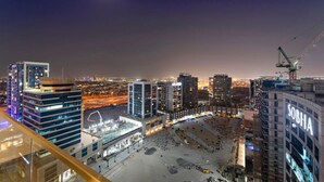 A nighttime cityscape with illuminated buildings, a construction site, and a crane. - Chic Studio Near Burj Khalifa, Dubai Opera & Dubai Mall w/ City Skyline Views (Dubai)