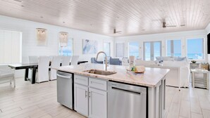 A spacious kitchen with a central island, white cabinetry, and a view of the ocean through large windows. - Orange Beach House East Beach Front, Private Pool, Sleeps up to 28, Quiet Beach! (Orange Beach)
