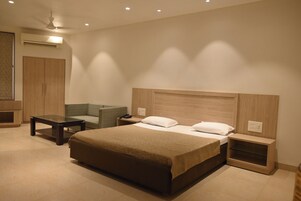 Una habitación de hotel moderna con una cama grande, un sofá, una mesita y una mesita de noche.
