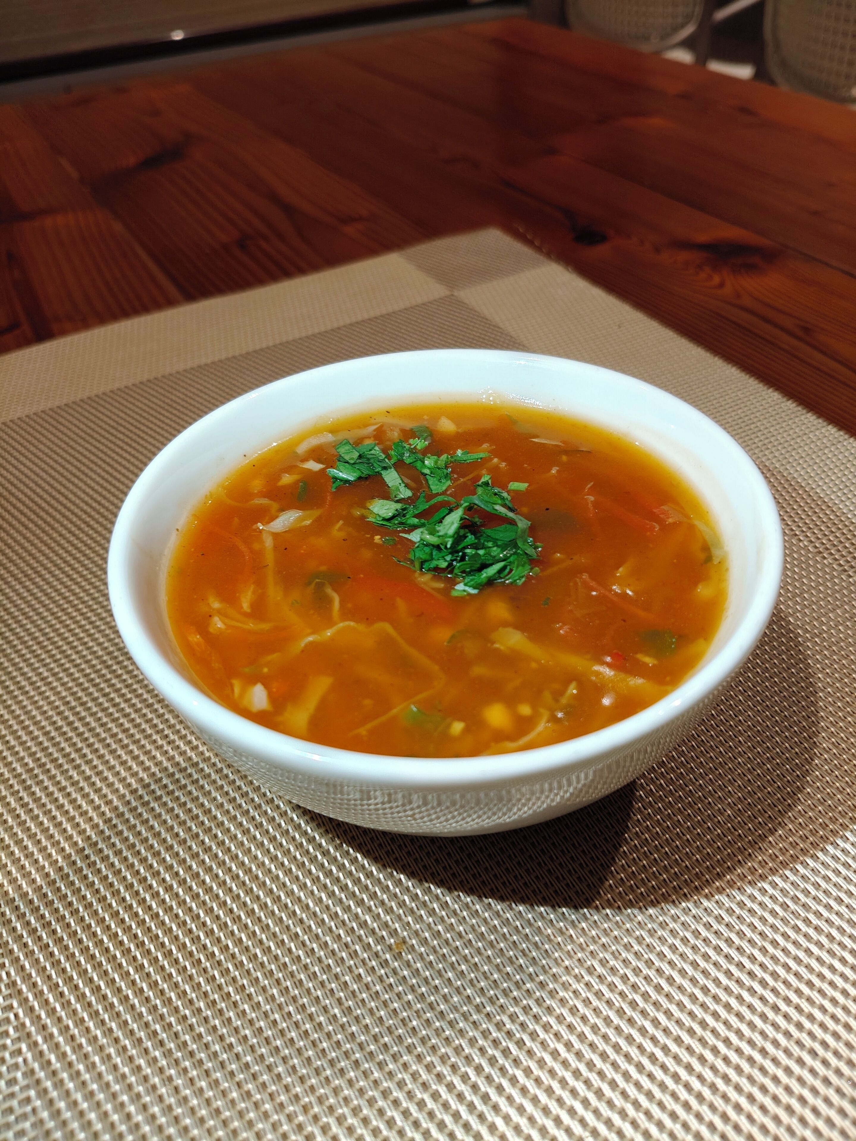 Una ciotola di zuppa su un sottopiattino intrecciato.