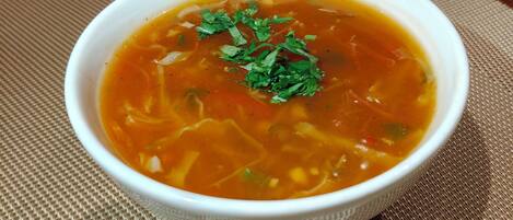 A bowl of soup on a woven placemat.