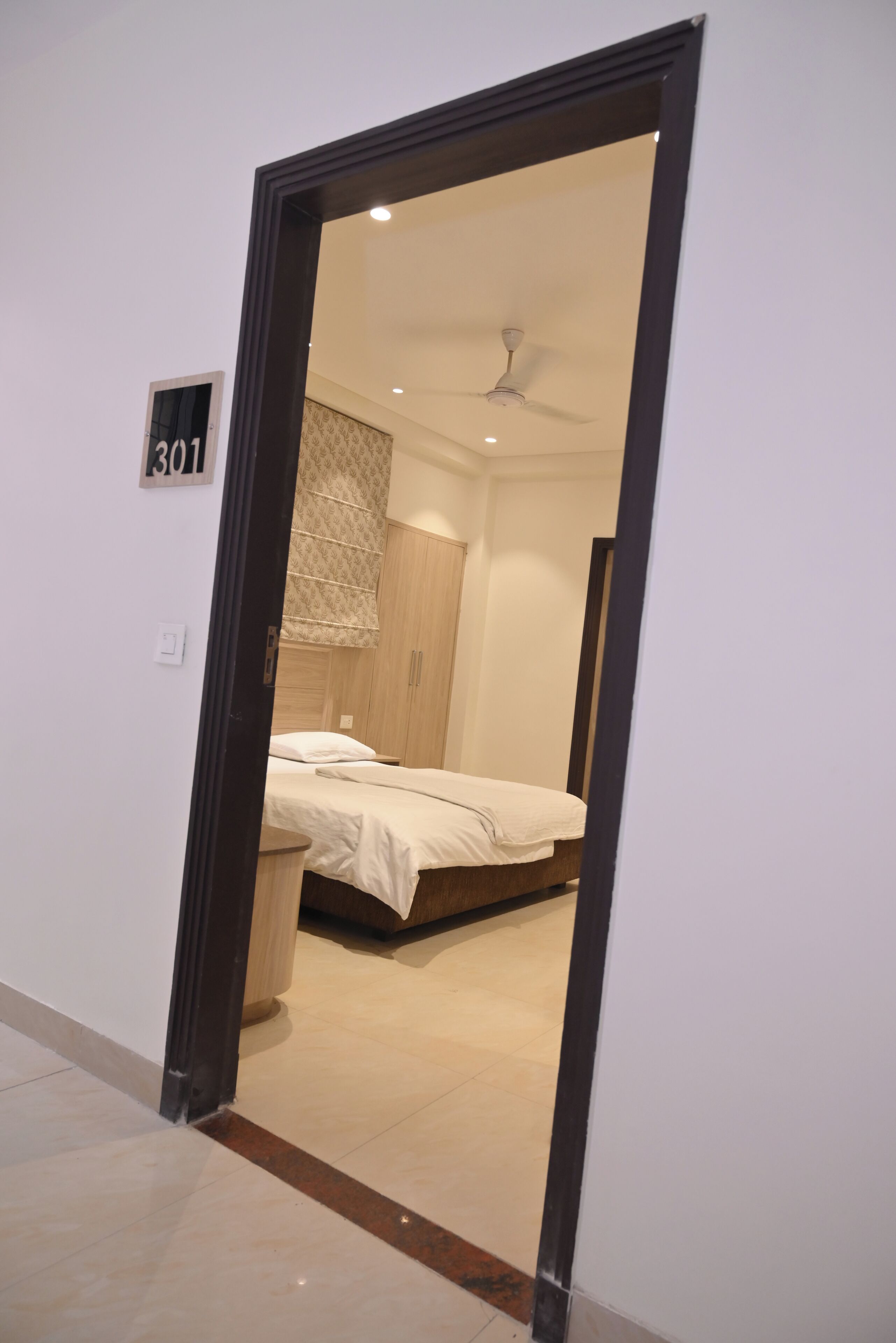 A hotel room with a bed, a ceiling fan, and a wardrobe.