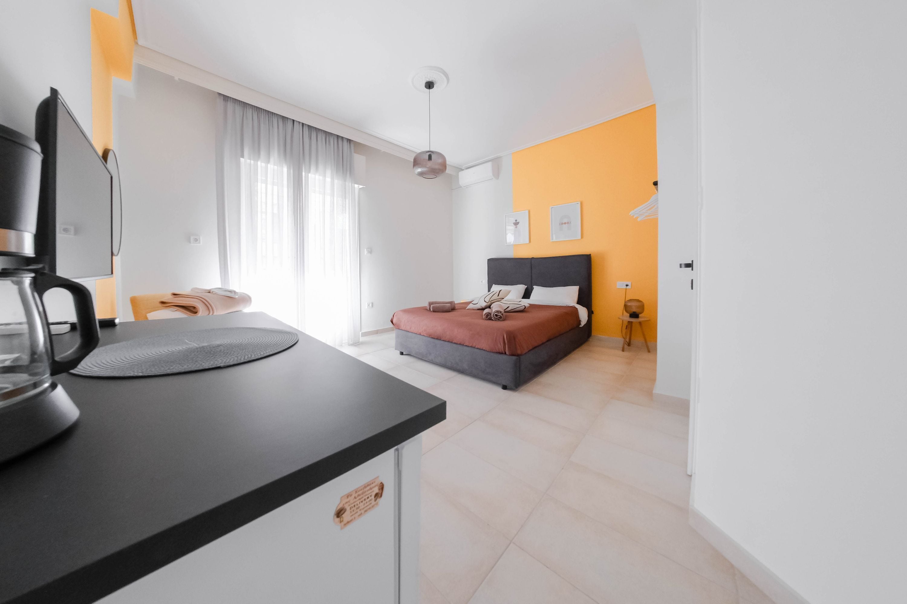 Une chambre d’hôtel moderne équipée d’un lit, d’un bureau avec une machine à café et offrant une vue sur la ville.