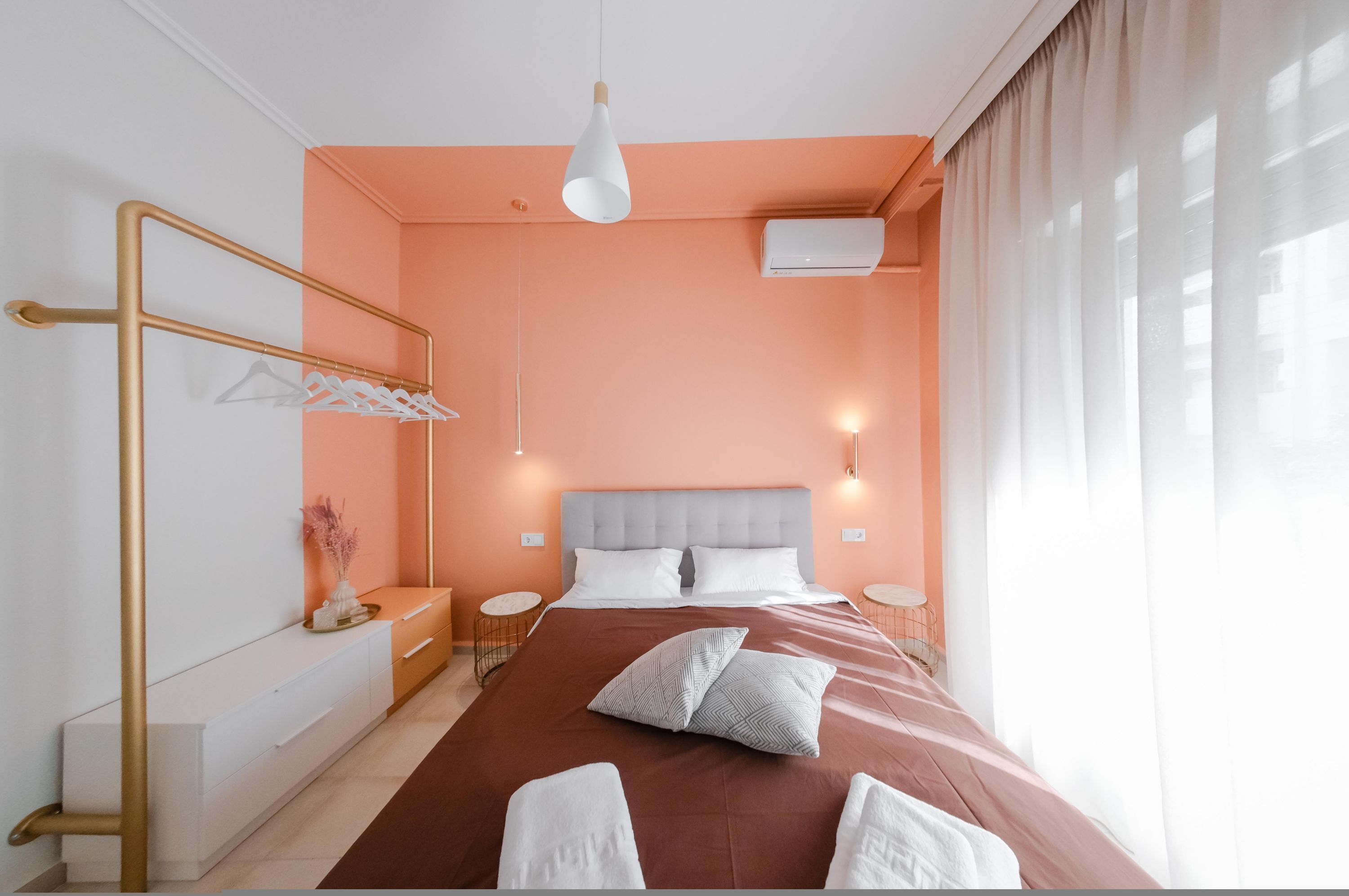 A modern bedroom with a large bed, a bedside table, a mirror, and a hanging light fixture.
